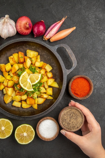 Free photo top view of tasty fried potatoes inside pan with different seasonings on the dark surface