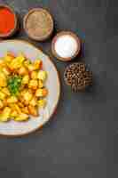 Free photo top view of tasty fried potatoes inside plate with seasonings on dark surface