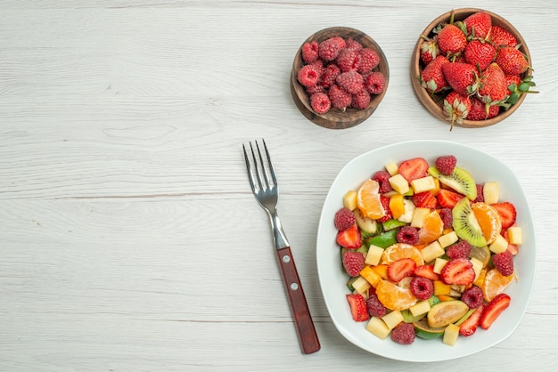 Top view tasty fruit salad sliced fruits on white background