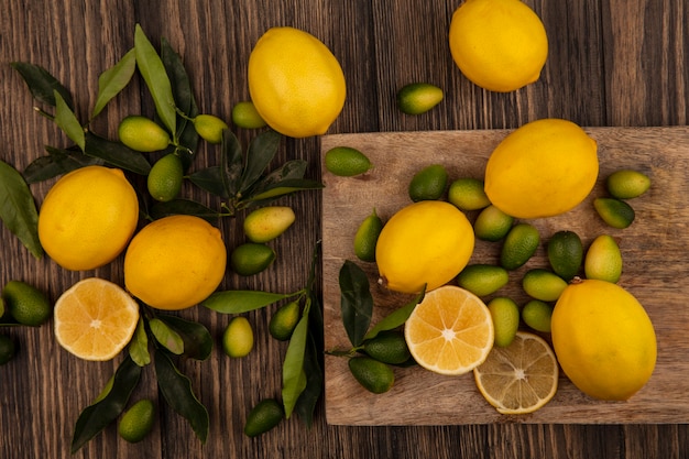 나무 표면에 나무 주방 보드에 고립 된 kinkans 및 레몬과 같은 맛있는 과일의 상위 뷰
