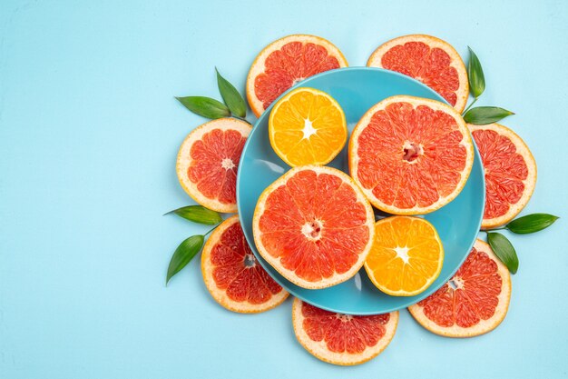 Top view of tasty grapefruits fruit slices on blue surface