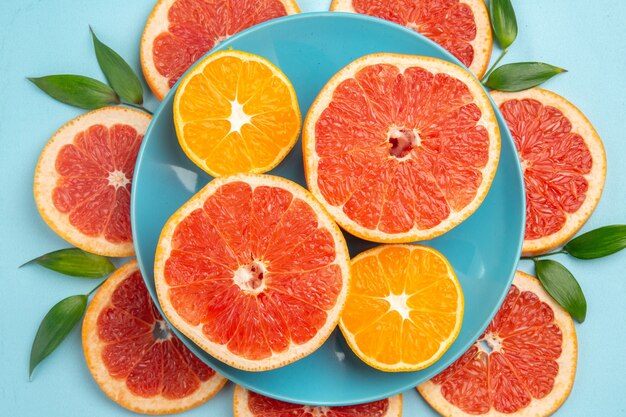 Top view of tasty grapefruits fruit slices on blue surface