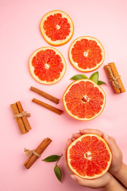 Top view of tasty grapefruits fruit slices with cinnamon on a pink surface