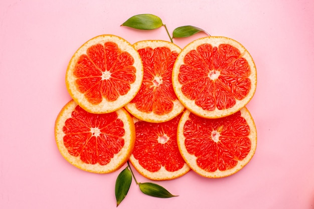 Top view of tasty grapefruits juicy fruit slices on pink surface