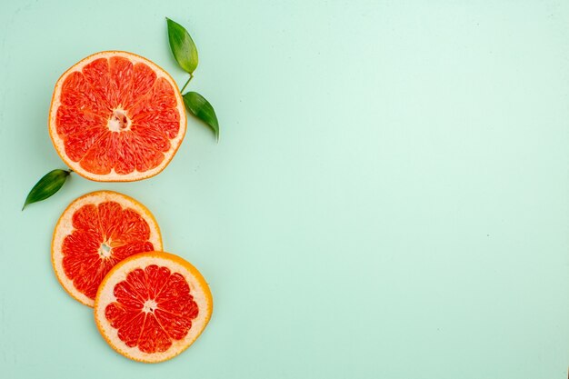 Top view of tasty grapefruits sliced juicy fruits on light-blue surface