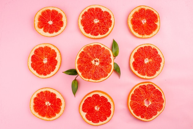 Free photo top view of tasty grapefruits sliced juicy fruits lined on pink surface