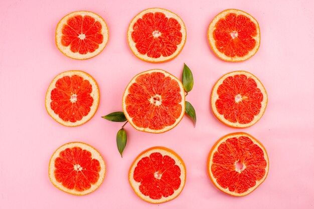 Top view of tasty grapefruits sliced juicy fruits lined on pink surface