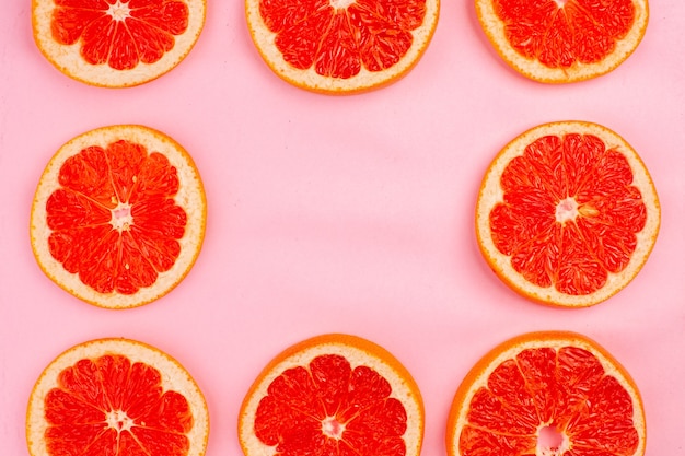 Top view of tasty grapefruits sliced juicy fruits lined on pink surface