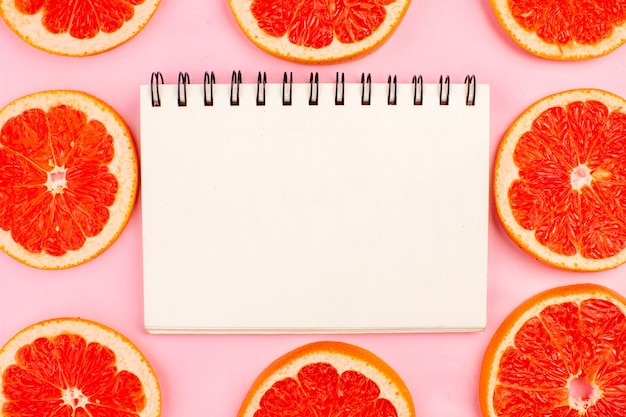 Free photo top view of tasty grapefruits sliced juicy fruits lined on the pink surface