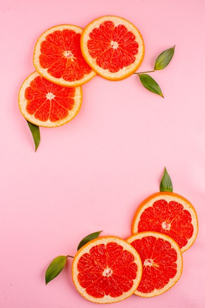 Top view of tasty grapefruits with cinnamon on pink surface