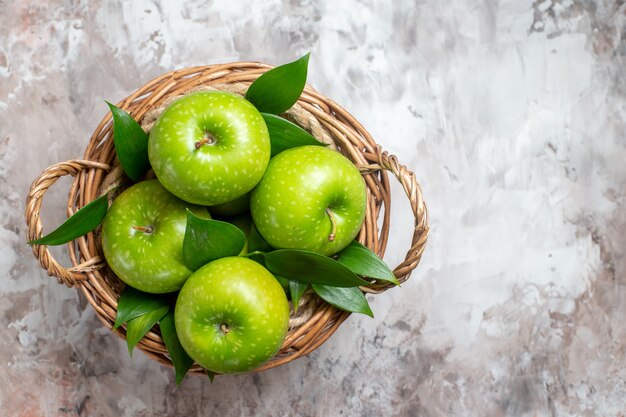 Вид сверху вкусные зеленые яблоки внутри корзины на светлом фоне