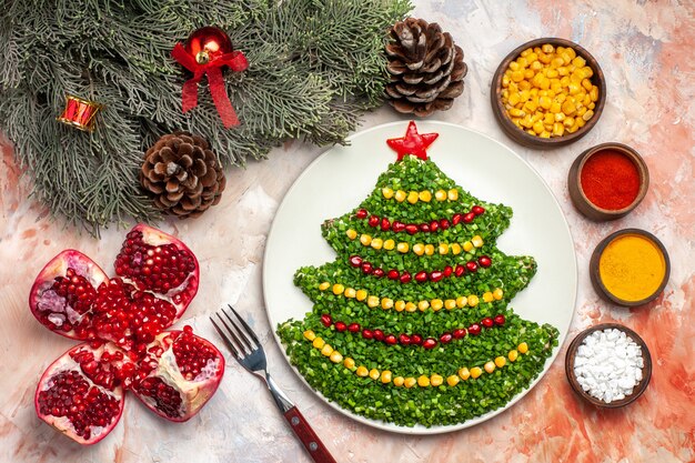 Top view tasty green salad in christmas tree shape with seasonings on light background