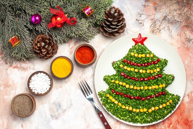 Top view tasty green salad in christmas tree shape with seasonings on light background