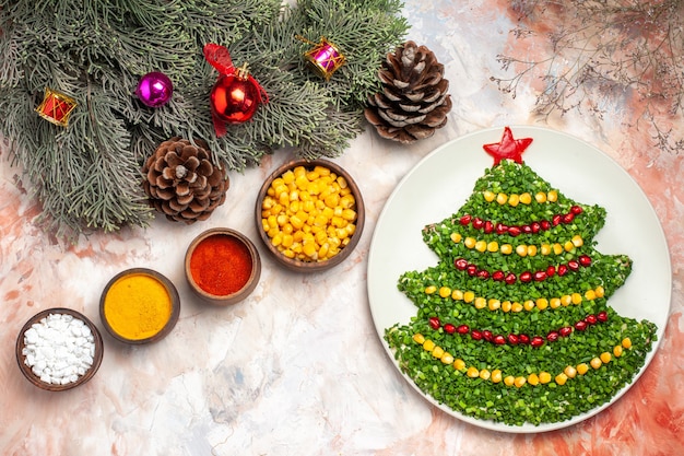 Top view tasty green salad in new year tree shape with seasonings on light background