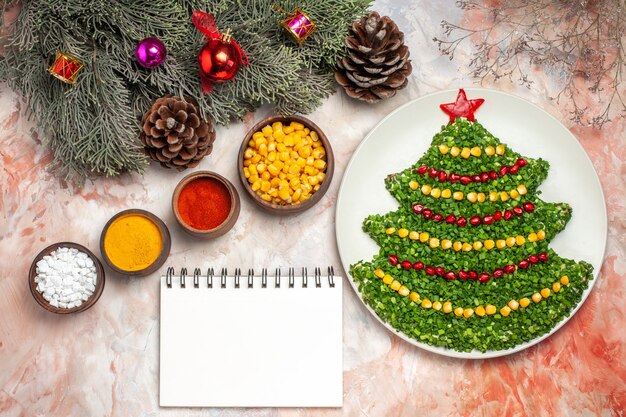 Top view tasty green salad in new year tree shape with seasonings on light background