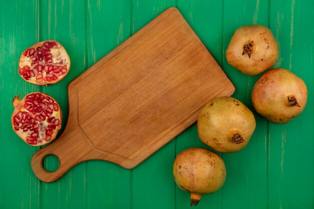 Top view of tasty half and whole pomegranates isolated on a green wooden wall with copy space