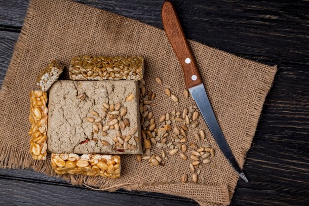 Top view of tasty halva with honey bars with peanuts and sunflower seeds on sackcloth