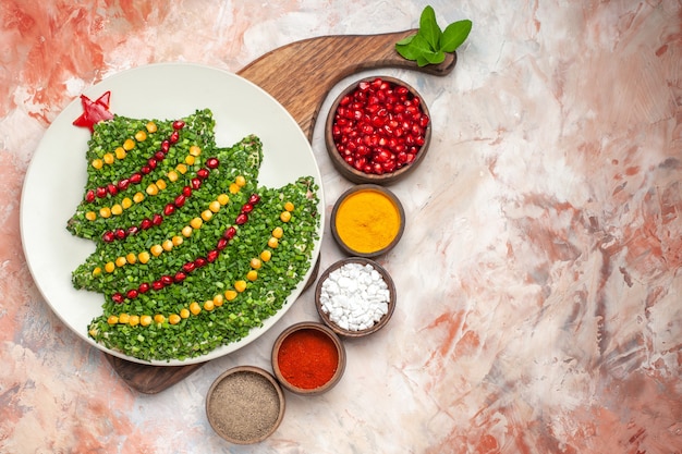 Top view tasty holiday salad in new year tree shape with seasonings on light background