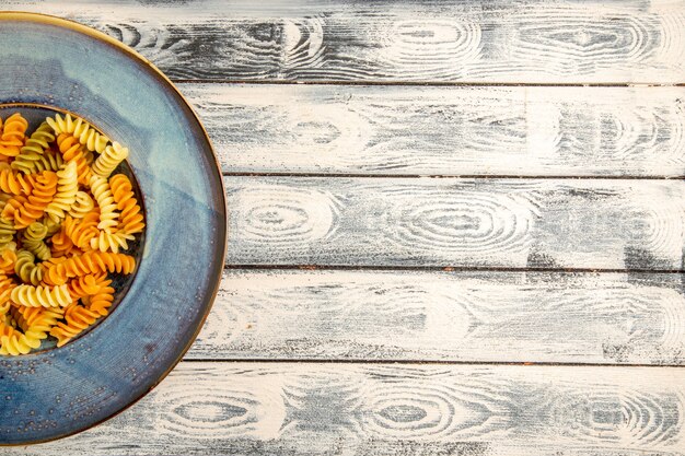 Top view tasty italian pasta unusual cooked spiral pasta on a grey wooden desk