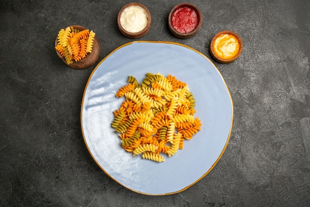 Top view tasty italian pasta unusual cooked spiral pasta with seasonings on grey