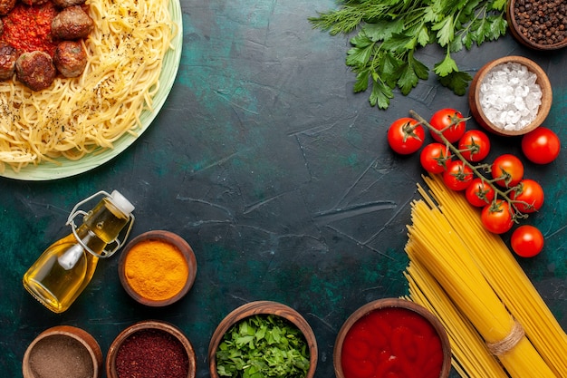 Foto gratuita vista dall'alto gustosa pasta italiana con polpette di carne e condimenti diversi sul pasto scrivania blu scuro