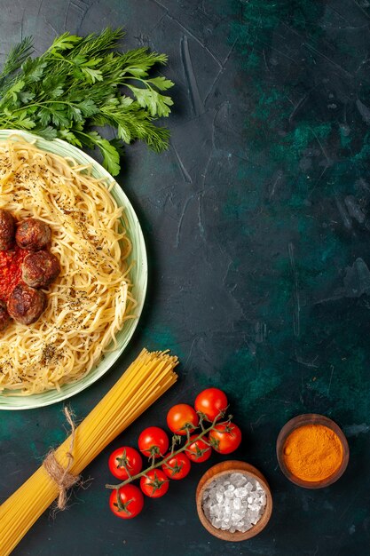 Top view tasty italian pasta with meatballs and greens on dark-blue background