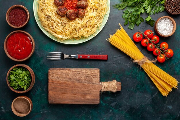 Top view tasty italian pasta with meatballs and seasonings on the dark blue background