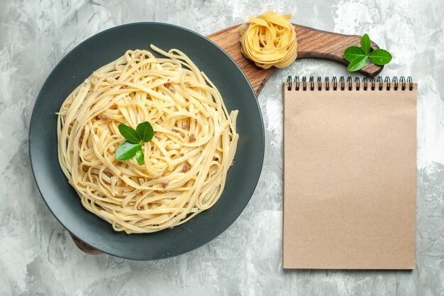 Top view tasty italian pasta with notepad on light background