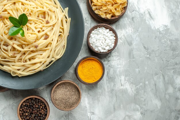 Top view tasty italian pasta with seasonings on a light background