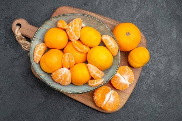 Вид сверху вкусные сочные мандарины внутри тарелки на сером фоне