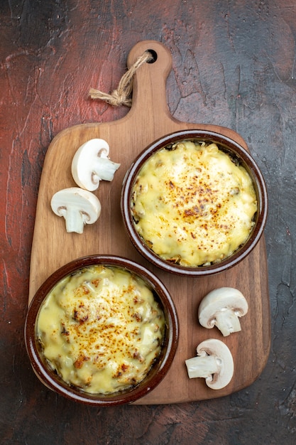 Top view tasty julienne in bowls cut mushroome on wood serving board on brown