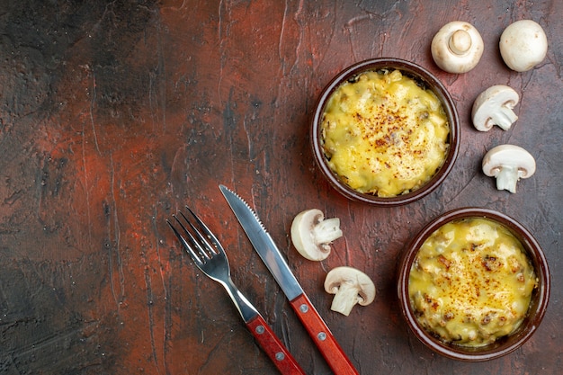 볼 나이프와 포크에 있는 맛있는 줄리엔은 복사 장소가 있는 갈색 테이블에 버섯을 잘라냅니다.