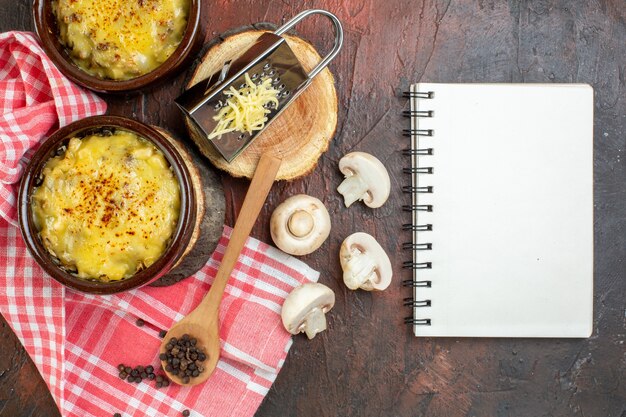 Top view tasty julienne in bowls mushrooms milk bowl notebook grater on wood board wooden spoon on dark red table