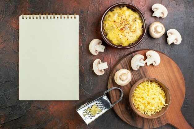 Top view tasty julienne in bowls raw mushrooms milk bowl grater notepad grated mosarella in bowl on cutting board on brown table