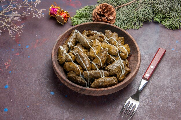 Top view tasty leaf dolma meat dish inside brown plate on a dark