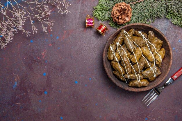 Top view tasty leaf dolma meat dish inside brown plate on dark