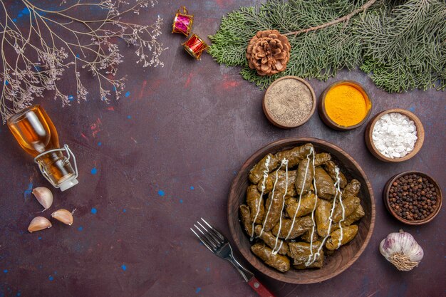 Top view tasty leaf dolma meat dish with seasonings on a dark