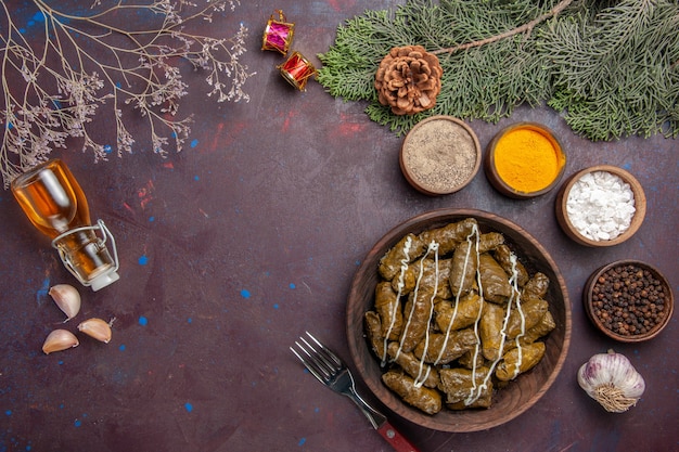 Top view tasty leaf dolma meat dish with seasonings on a dark