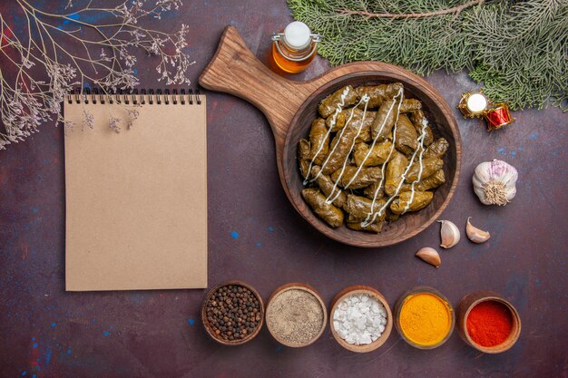 Top view tasty leaf dolma meat dish with seasonings on a dark