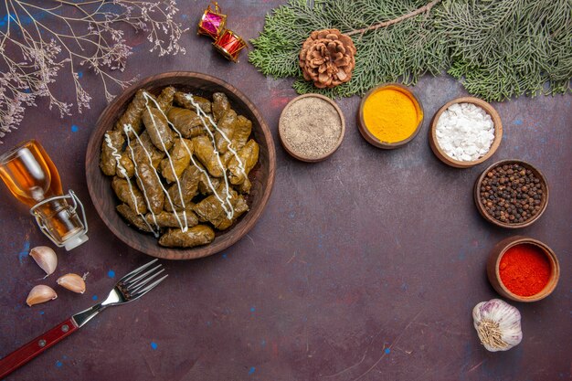 Top view tasty leaf dolma meat dish with seasonings on dark