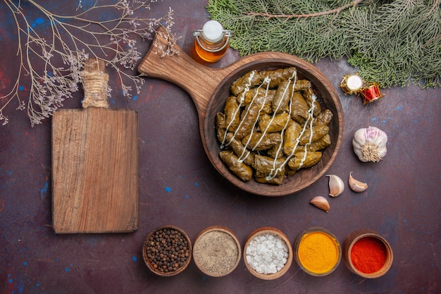 Top view tasty leaf dolma meat dish with seasonings on dark