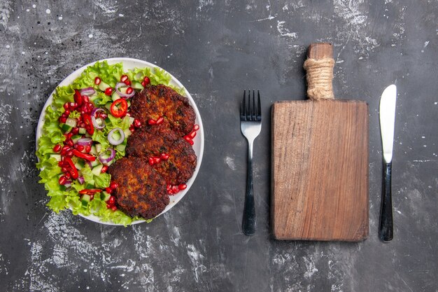 Top view tasty meat cutlets with fresh salad on grey desk photo meat dish food