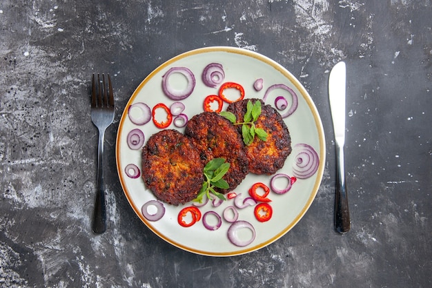 Вид сверху вкусные мясные котлеты с луковыми кольцами на сером фоне еда кухня фото