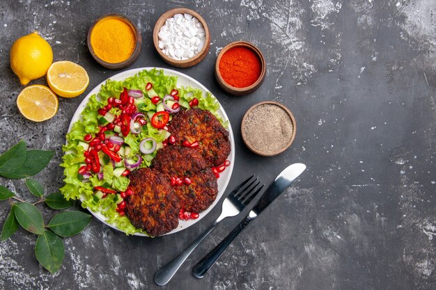 Бесплатное фото Вид сверху вкусные мясные котлеты с салатом и приправами на сером фоне фото еда блюдо еда