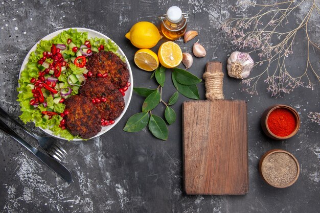 Вид сверху вкусные мясные котлеты с овощным салатом на сером фоне блюдо фото еда еда
