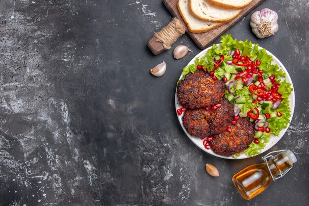 Вид сверху вкусные мясные котлеты с овощным салатом на сером столе фото еда еда