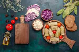 Бесплатное фото Вид сверху вкусной мясной муки с капустой и помидорами под названием долма с маслом на темно-синем столе