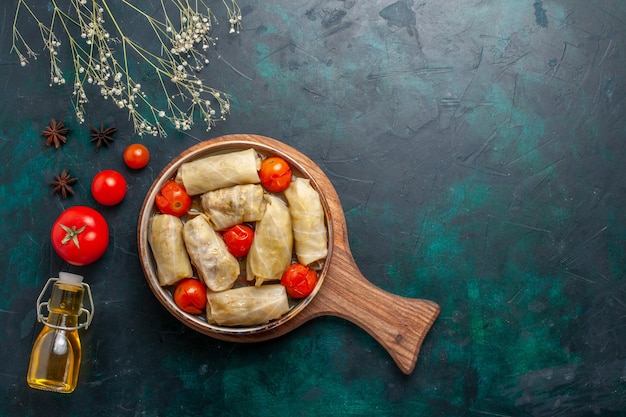 Бесплатное фото Вид сверху вкусной мясной еды с капустой и помидорами под названием долма с оливковым маслом на темно-синем столе