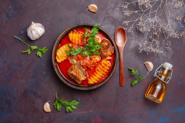 Top view tasty meat sauce soup with greens and sliced potatoes on black