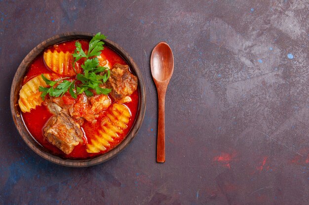 Top view tasty meat sauce soup with greens and sliced potatoes on black